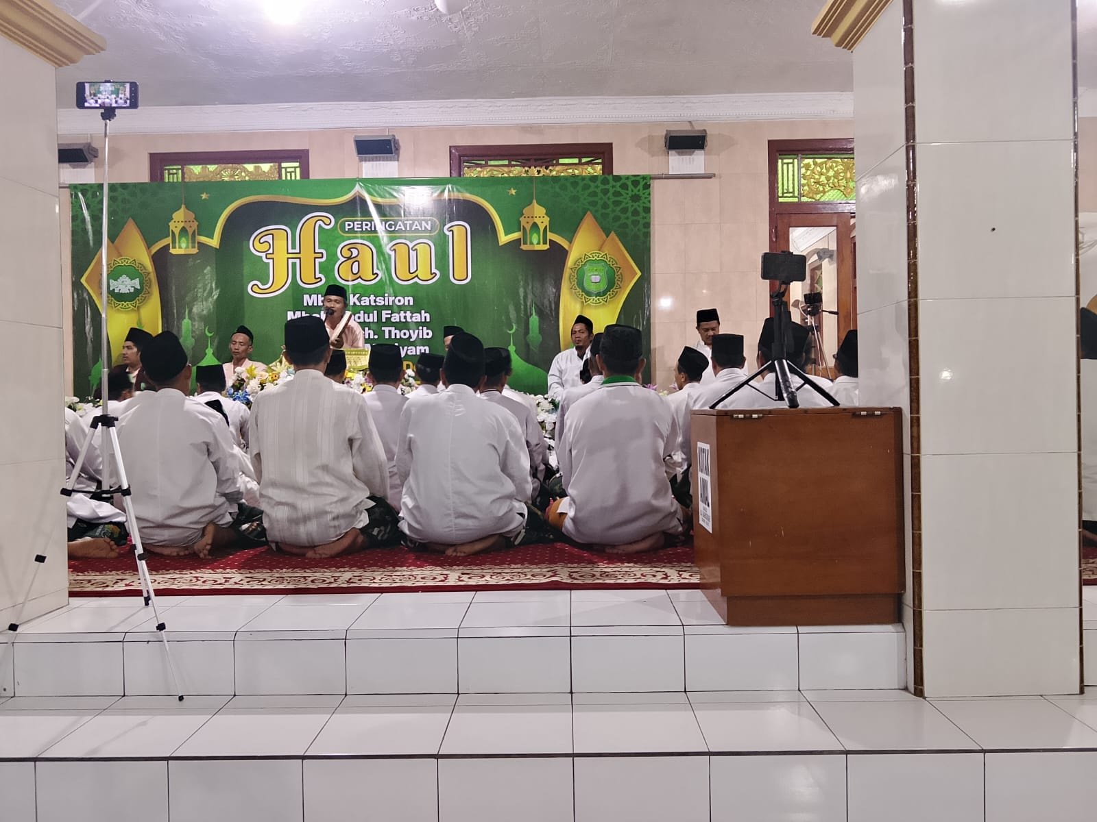 Suasana jamaah duduk rapi di serambi Masjid Al-Barokhah dengan latar lampu hias yang terang