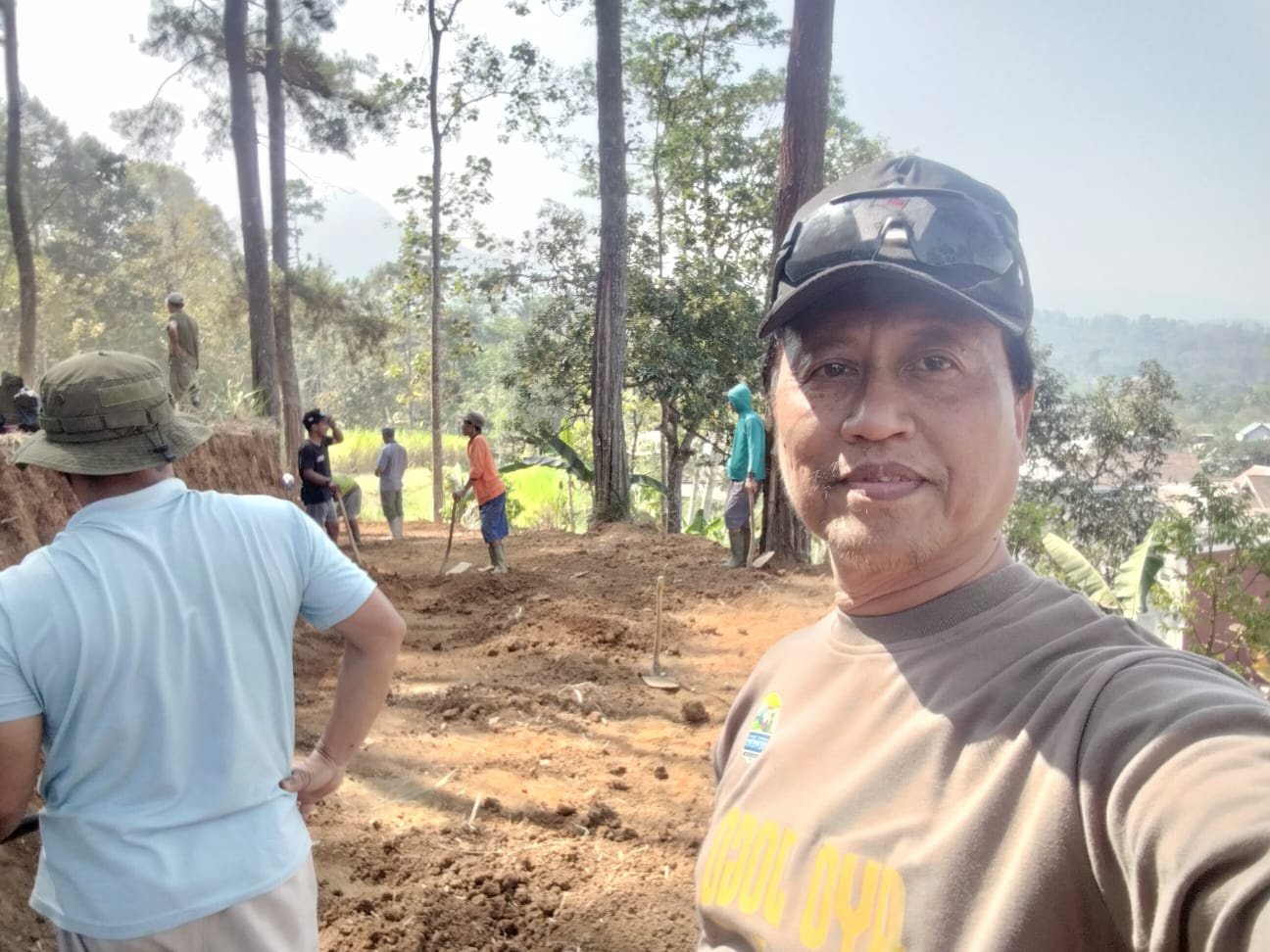 Warga bergotong royong membersihkan gulma di sepanjang jalur pendakian Puncak Srege. Rumput dan semak belukar dibersihkan dengan cangkul, sementara beberapa warga lain menyingkirkan batu dari jalur setapak.